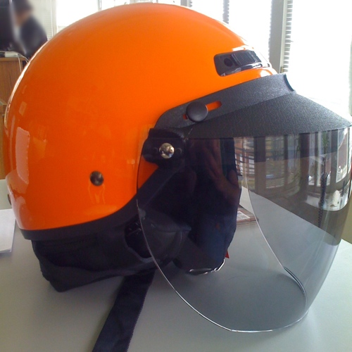 A bright orange open-face scooter helmet with a clear visor